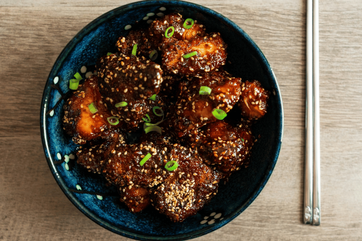 Ilustrasi sayap ayam kecap berlapis saus cokelat gelap, disajikan sebagai hidangan gurih di atas piring.