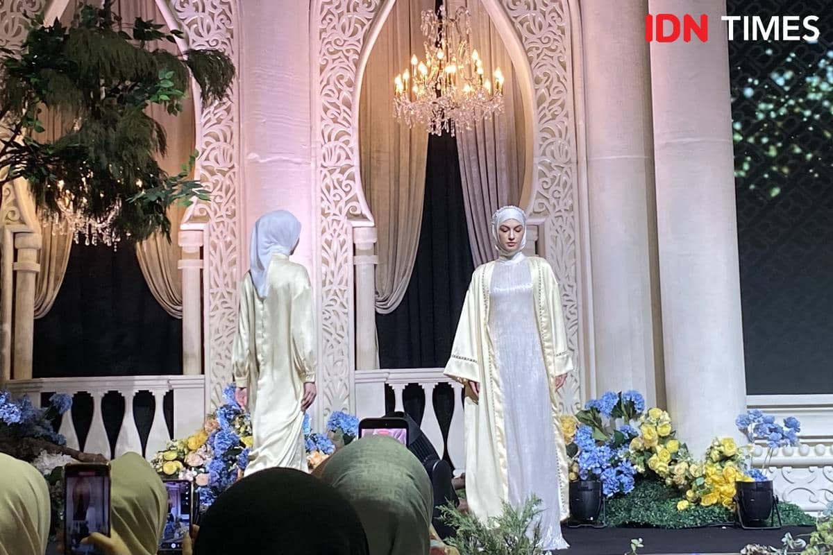 Seorang model berjalan di runway mengenakan abaya dengan paduan busana berlapis sebagai bagian dari look peragaan.