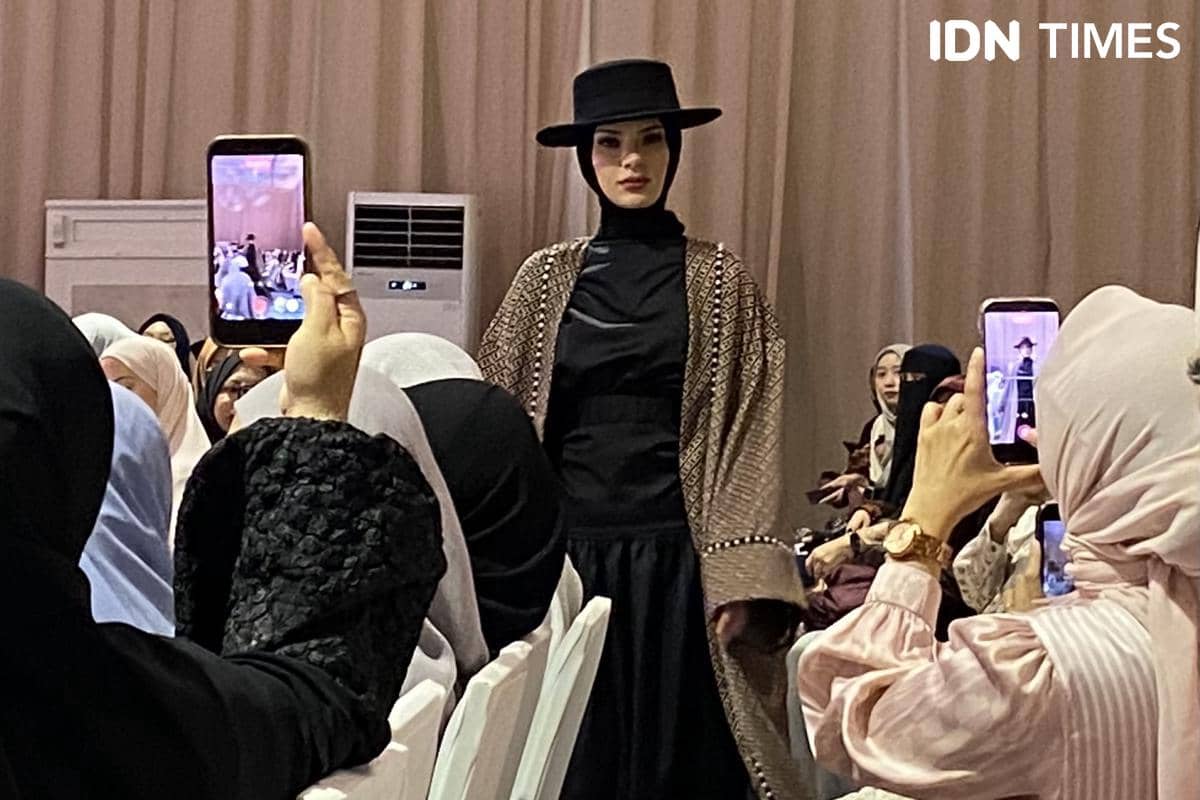 Topi bertepi lebar berwarna hitam digunakan dalam salah satu look Benang Jarum The Abaya Collection.