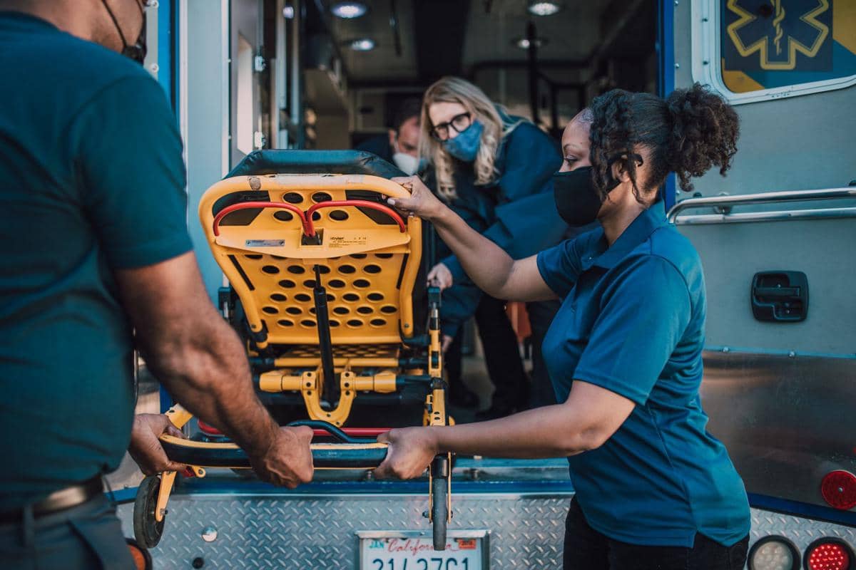 Dua petugas ambulans mendorong brankar berisi pasien untuk menggambarkan penanganan darurat stroke.