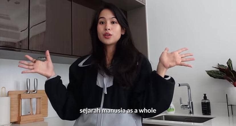 Potret Maudy Ayunda dengan ekspresi tenang menghadap kamera dalam pencahayaan lembut dengan latar sederhana.