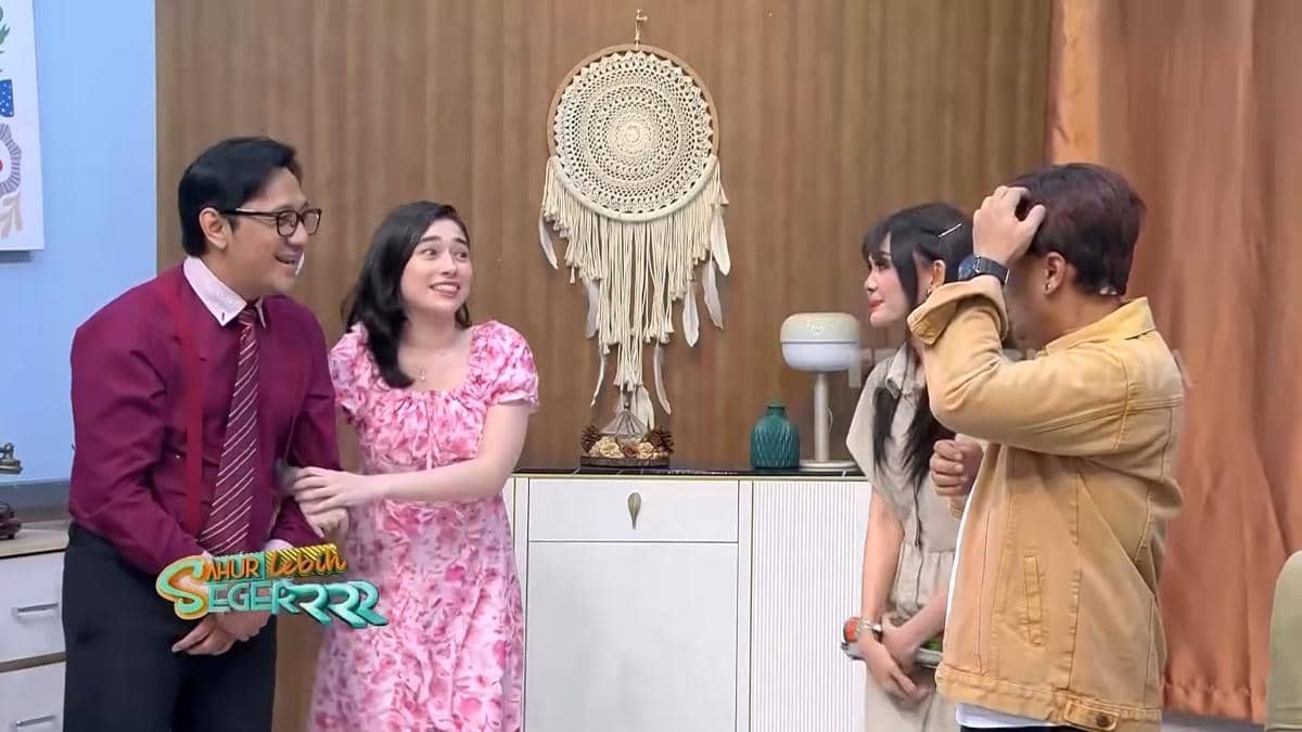Andre Taulany dan Amanda Rigby duduk berdampingan di studio sambil mengisi program televisi Trans7 bersama.