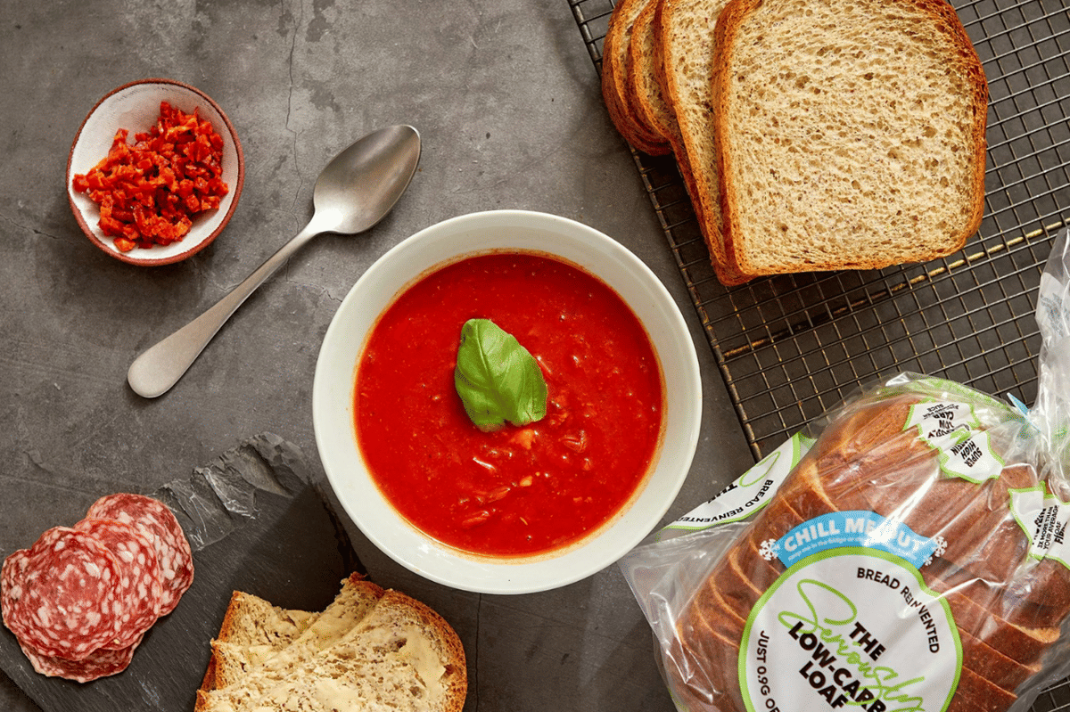 Aneka bahan untuk tomato soup dan grilled cheese tersusun di atas meja sebagai ilustrasi hidangan rumahan.