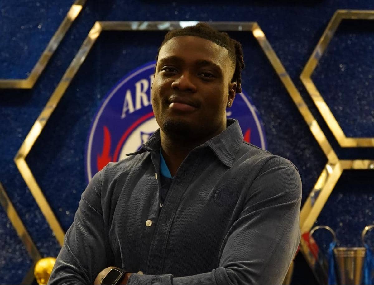 Potret striker asing baru Arema FC, Oluwasegun Samuel Otusanya, mengenakan seragam klub dengan latar area latihan.