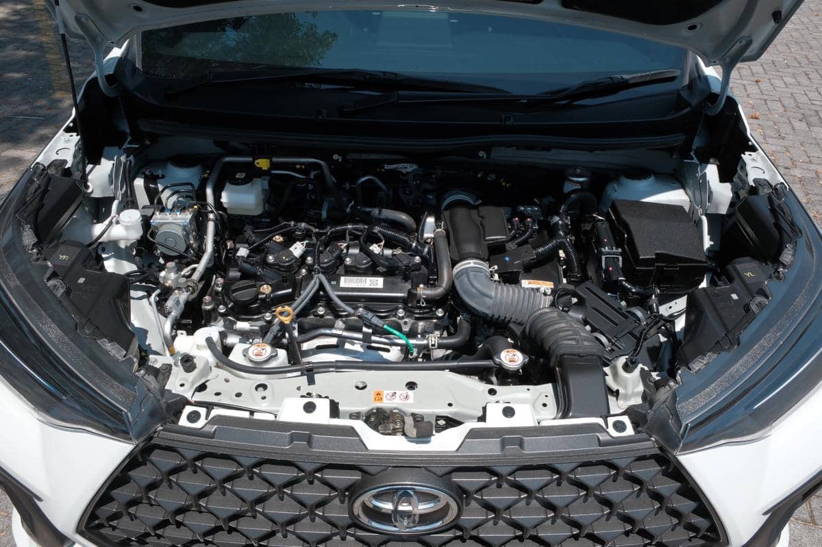 Ruang mesin Toyota Veloz Hybrid dengan komponen mesin bensin dan sistem hybrid tersusun rapi di bawah kap kendaraan.