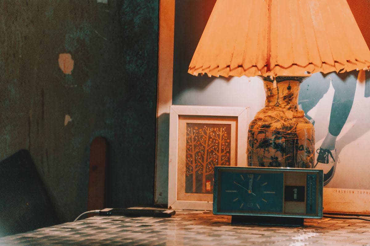 Lampu meja memancarkan cahaya hangat di kamar tidur, menciptakan suasana nyaman untuk tidur lebih nyenyak.