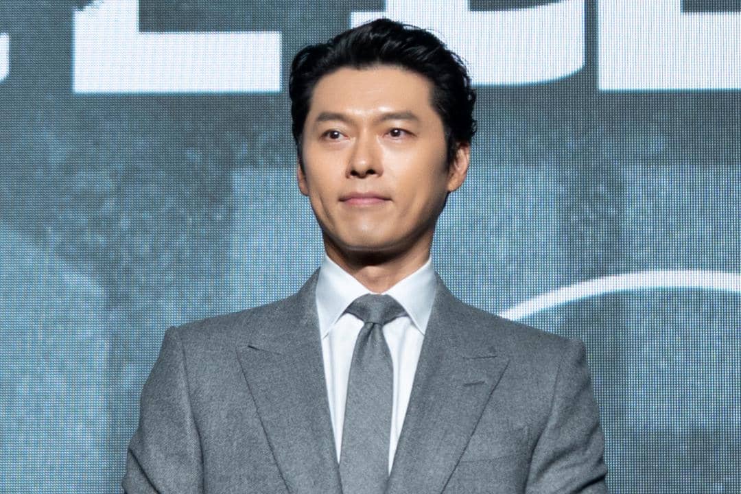 Hyun Bin mengenakan jas gelap dan kemeja putih saat menghadiri konferensi pers para pemain Made in Korea 2.