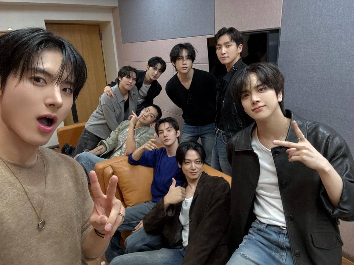 Potret Sangyeon THE BOYZ saat pulang dari wajib militer, mengenakan seragam dan baret hitam di luar ruangan.