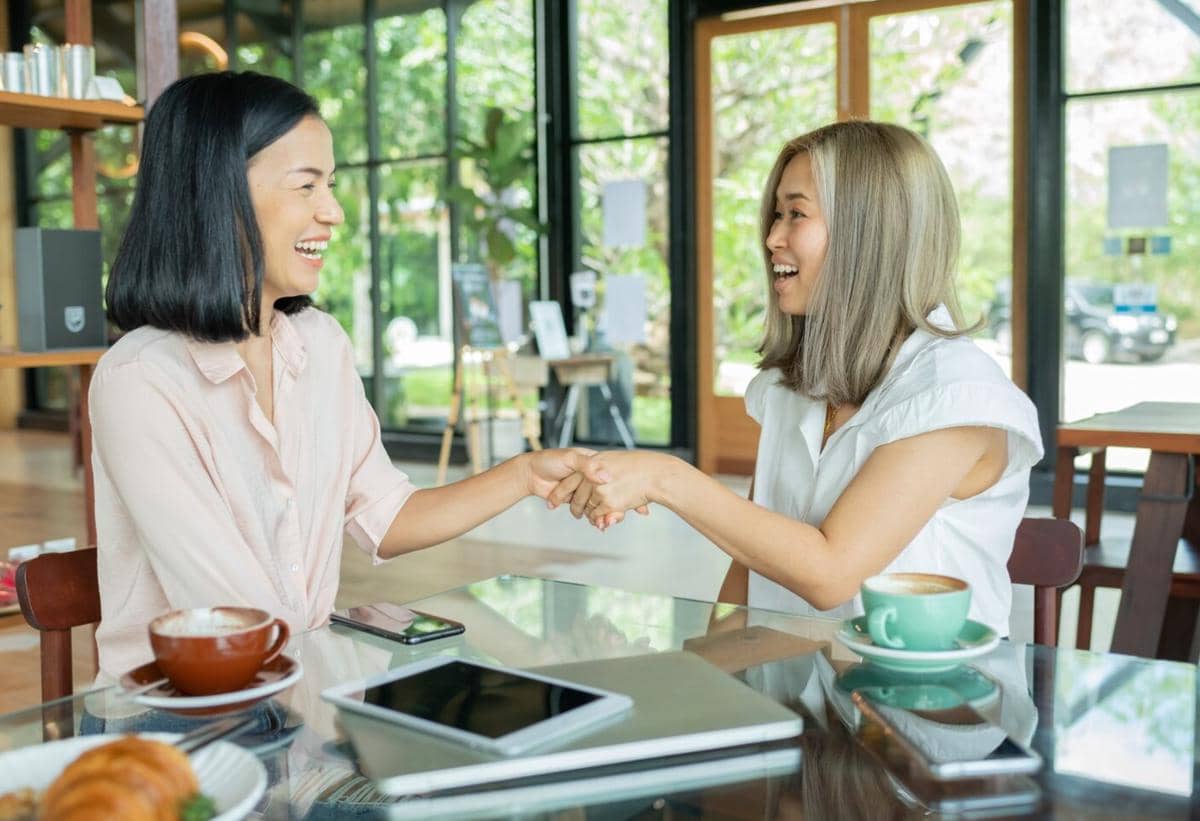 Ilustrasi dua perempuan berdiri berdekatan sambil saling mendukung, menggambarkan kepedulian dan solidaritas antarsesama.