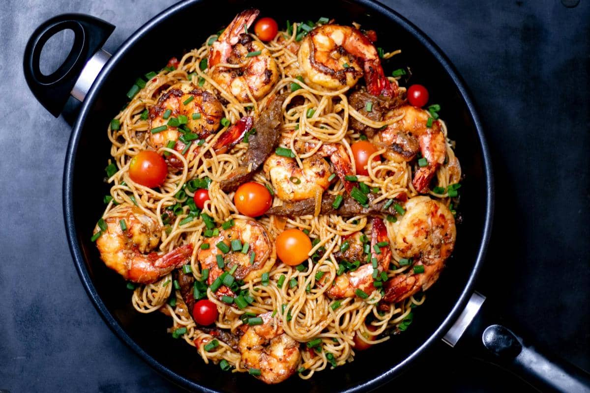 Sepiring spaghetti dengan saus bolognese dan udang, disajikan di atas piring putih sebagai ilustrasi hidangan pasta.