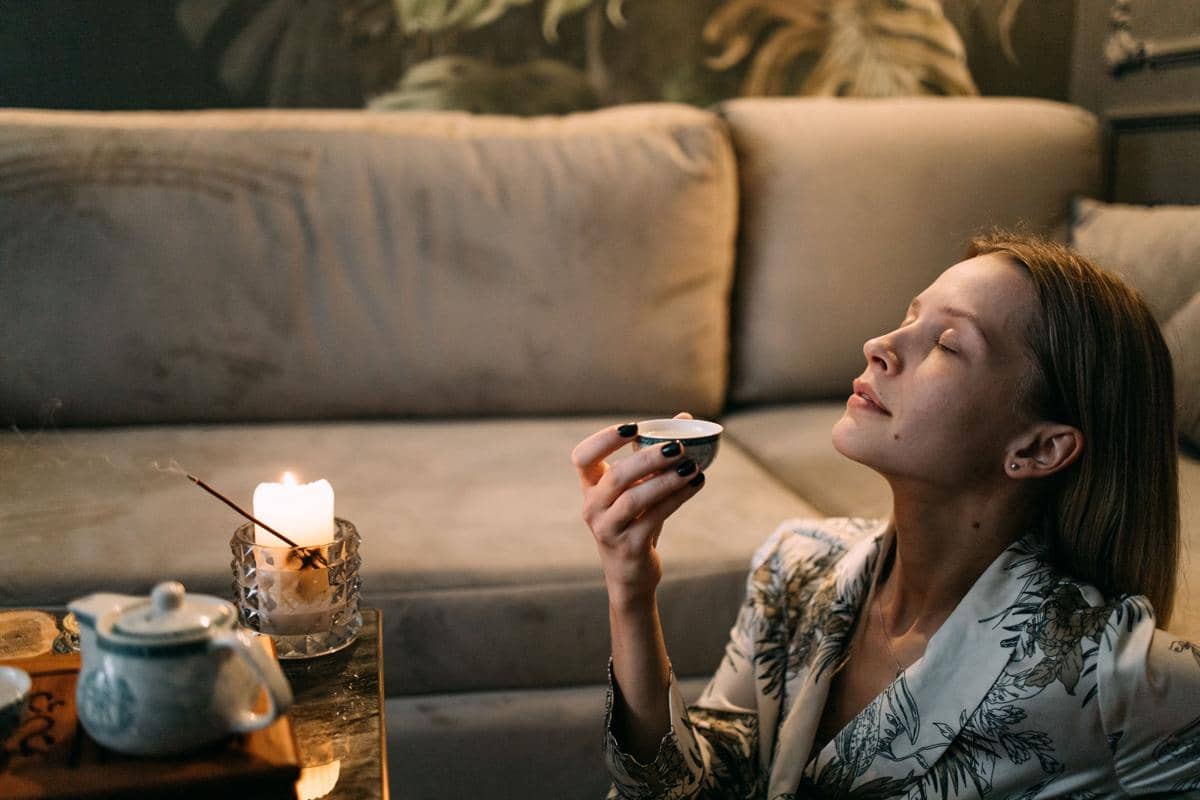 Momen tenang menikmati ritual minum teh yang menenangkan pikiran di sudut sofa rumah.