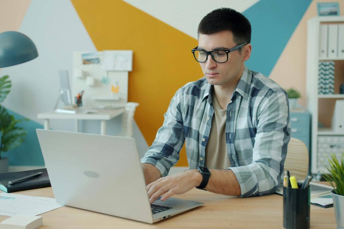 Pria berkacamata di depan laptop