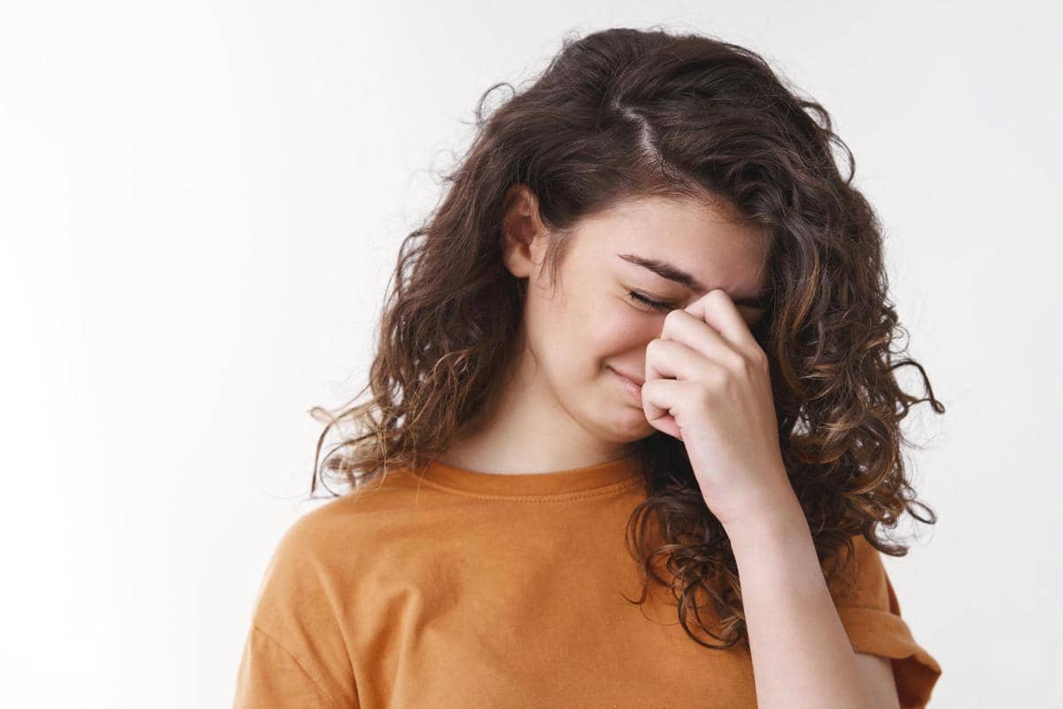 Gadis menyembunyikan air mata terisak menyentuh hidung menutup mata mengerutkan kening merasa tersinggung berdiri dengan murung