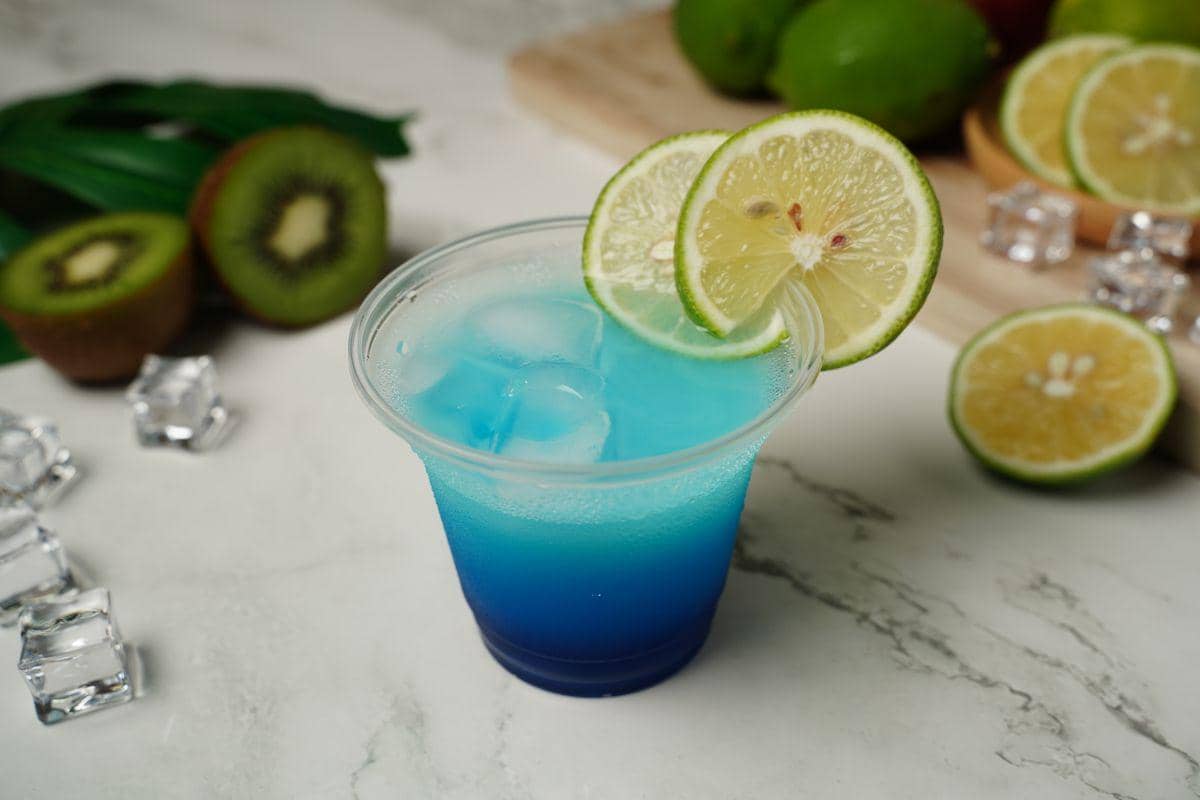 Minuman biru rasa leci dengan garam disajikan dalam gelas, menawarkan tampilan segar dengan warna mencolok.