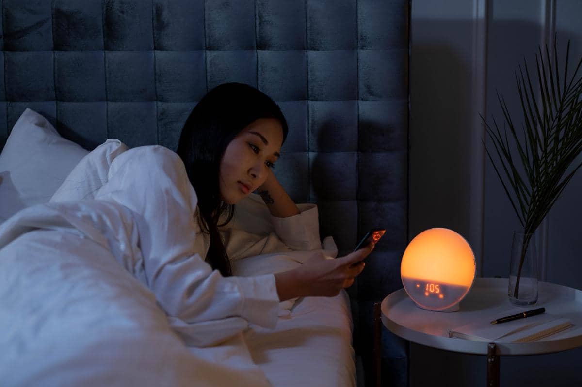 Perempuan bermain ponsel di kamar