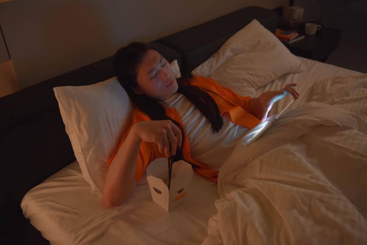 Perempuan makan di tempat tidur