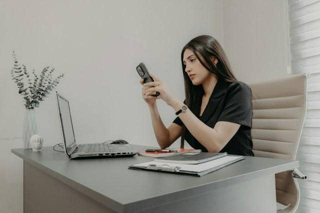 Ilustrasi pekerja mengecek status BSU lewat ponsel di kantor