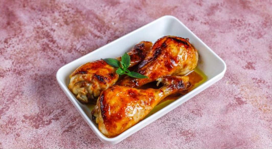 Ilustrasi hidangan ayam panggang madu sereh dengan potongan ayam berbumbu, serai, dan pelengkap di atas piring.