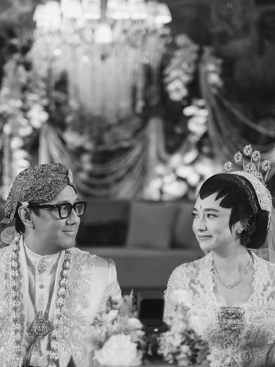 Andre Taulany dan Amanda Rigby berpose dalam potret pernikahan dengan busana pengantin di lokasi acara.