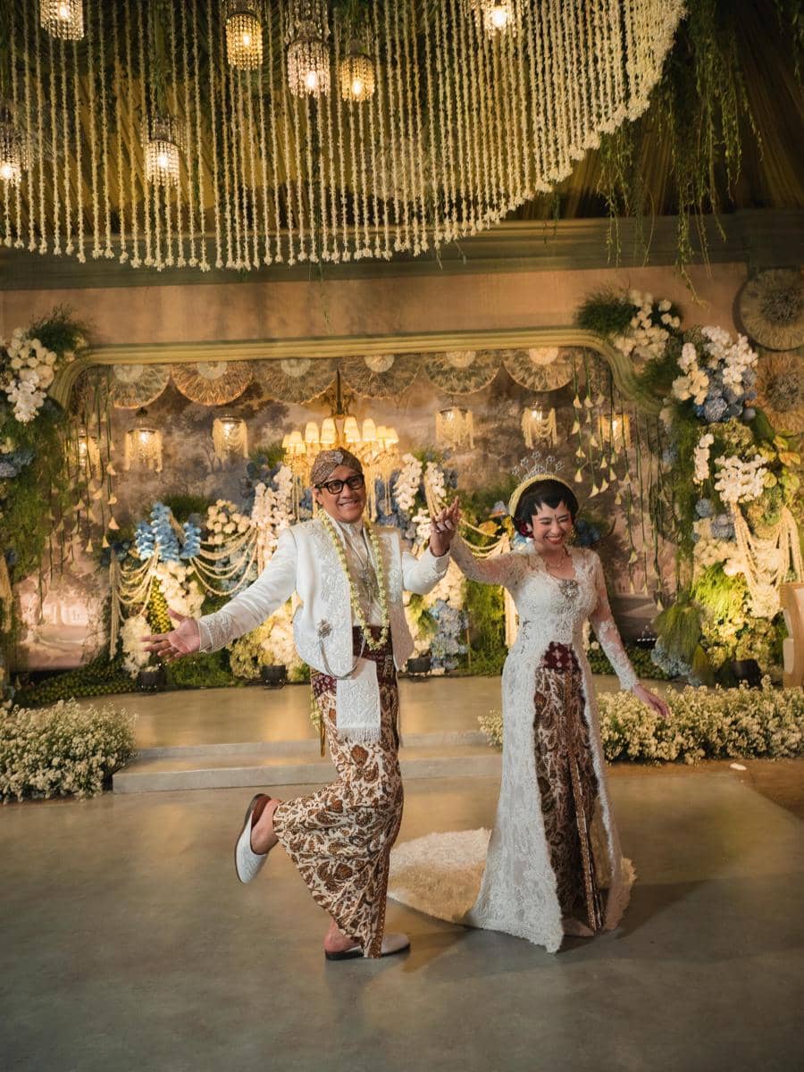Andre Taulany dan Amanda Rigby berpose dalam potret bertema pernikahan dengan busana pengantin serba putih.