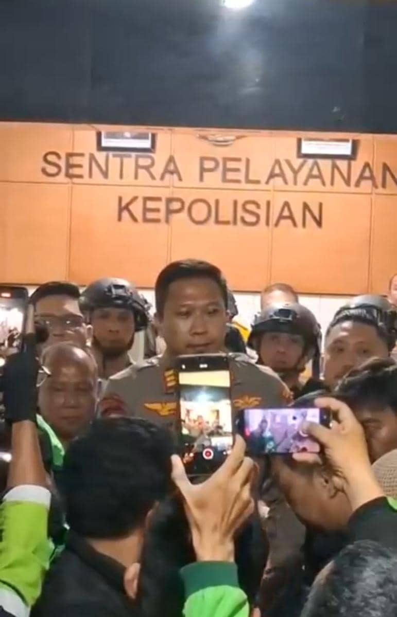 Ratusan pengemudi ojek online berkumpul di depan Polsek Mamajang, Makassar, pada malam hari dengan motor terparkir.