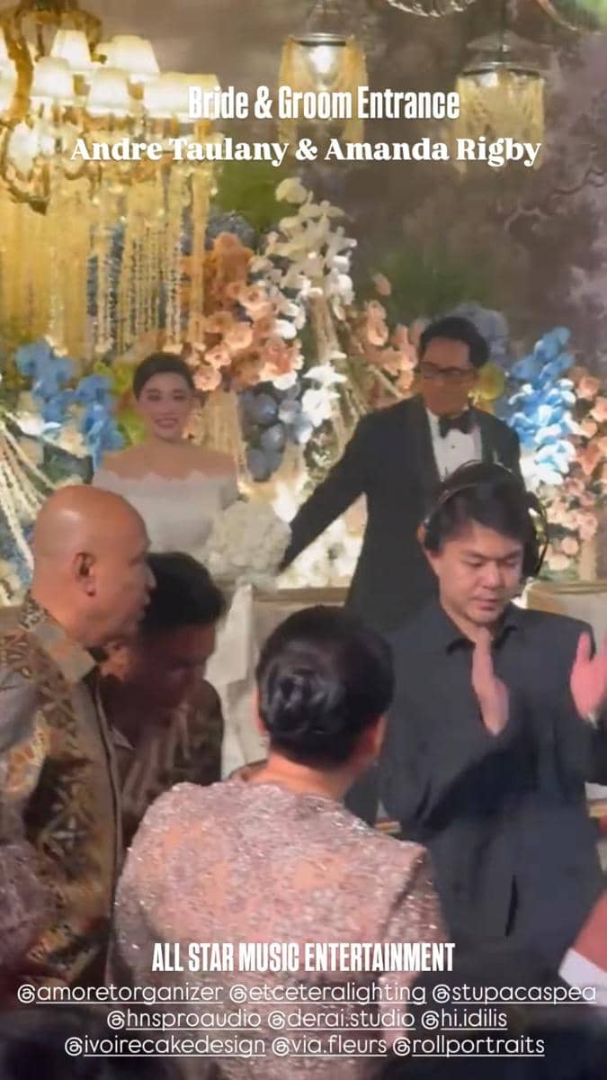 Andre Taulany dan Amanda Rigby berada di resepsi pernikahan dengan busana formal bersama para tamu.