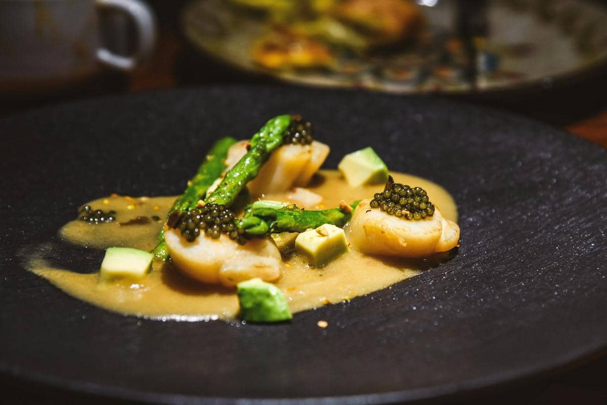 Seporsi dover sole tersaji di atas purée jamur dengan saus truffle, disajikan rapi di piring putih.
