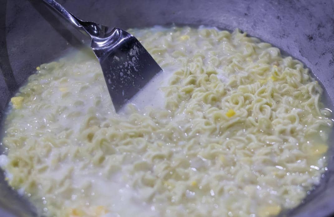 Mi instan sedang dimasak dalam panci di atas kompor sebagai ilustrasi kegiatan memasak di dapur rumah.
