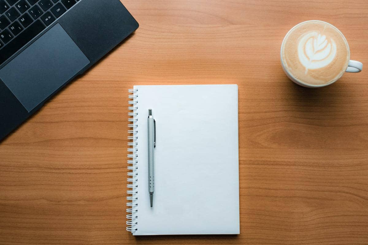 Ilustrasi buku pena kopi dan laptop diatas meja (unsplash.com/ dlxmedia.hu)