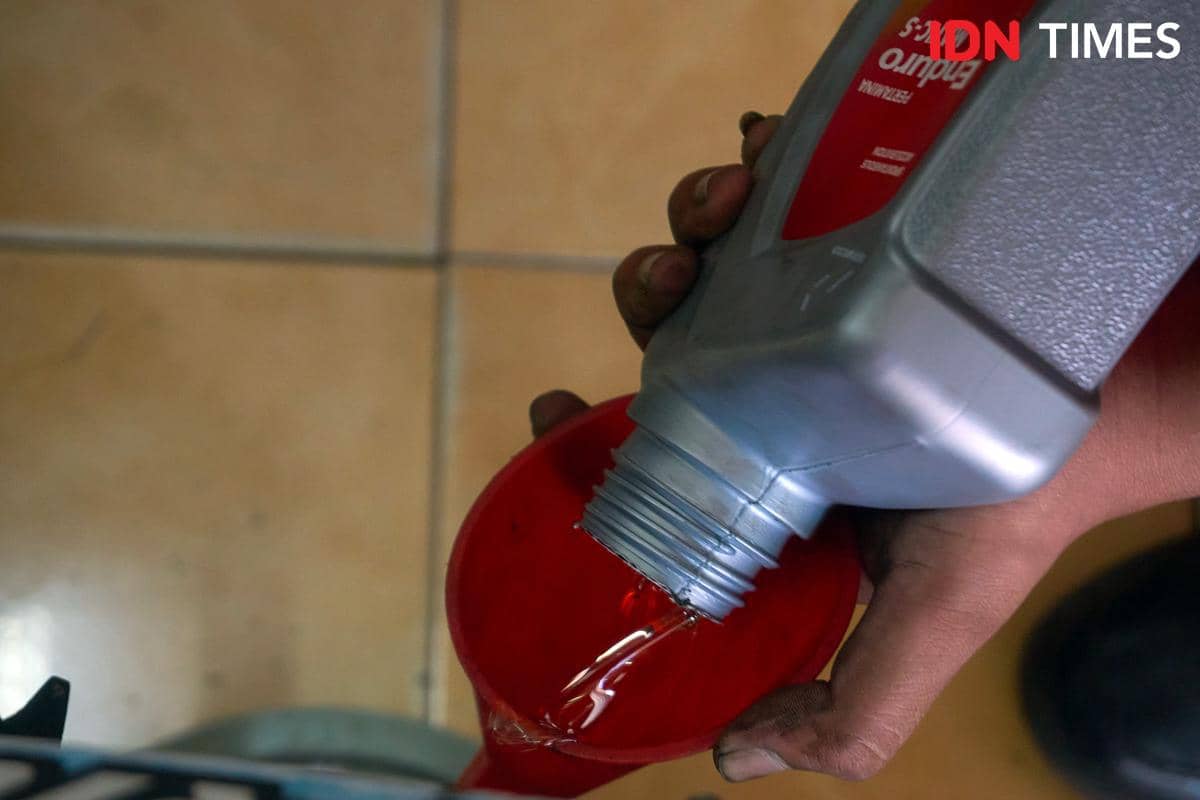 Pelumas dituangkan saat servis sepeda motor di Karya Speed, Rabu (16/9/2026). Bengkel tersebut dikembangkan melalui program Enduro Home Serv
