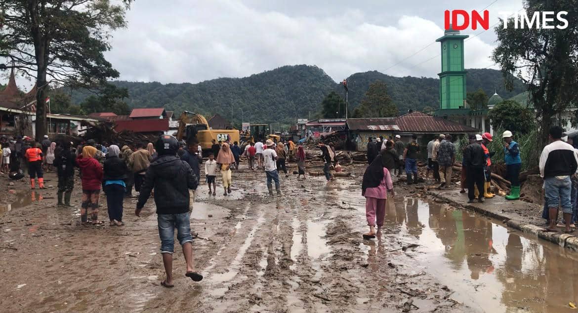 Material lumpur, batu, dan kayu sisa banjir bandang menutup badan jalan saat proses evakuasi di Kabupaten Solok.