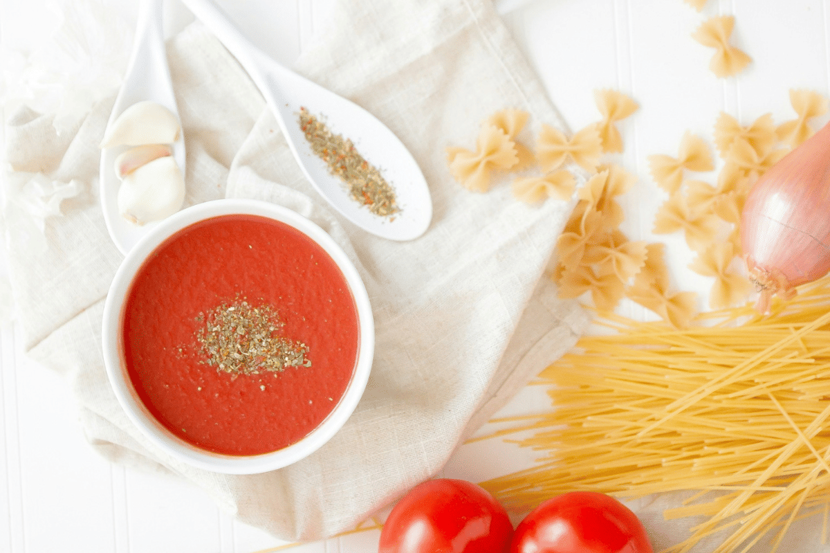 Semangkuk saus tomat merah kental dengan daun basil segar sebagai ilustrasi saus tomat ala Prancis.