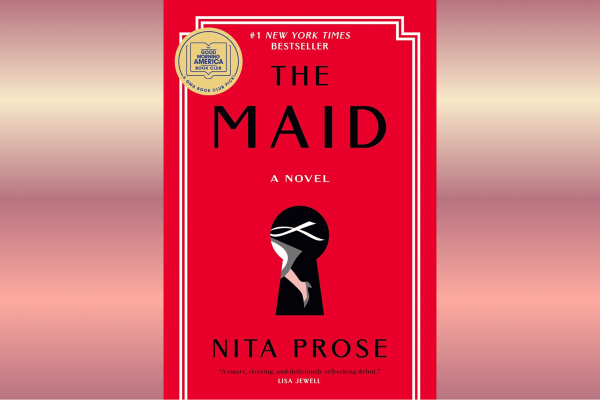 Sampul buku The Maid karya Nita Prose dengan judul putih besar di atas latar biru dan ilustrasi bunga.