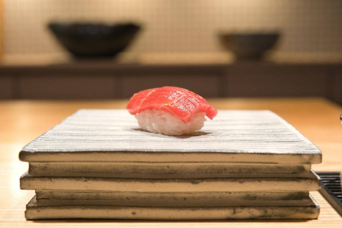 Aneka sushi Jepang tersaji rapi di atas piring, dengan potongan ikan, nasi, dan hiasan daun hijau segar.