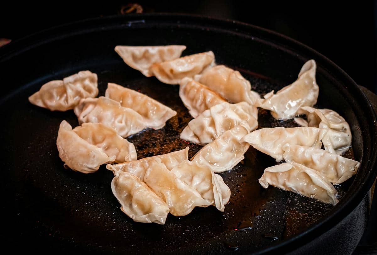 Ilustrasi proses membuat sichuan pork wonton, pangsit isi daging babi khas Sichuan yang disajikan dalam mangkuk.