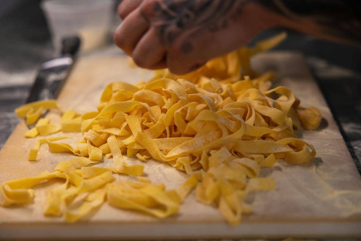 Ilustrasi sepiring pasta pappardelle berbentuk pita lebar yang disajikan sebagai hidangan khas Italia.