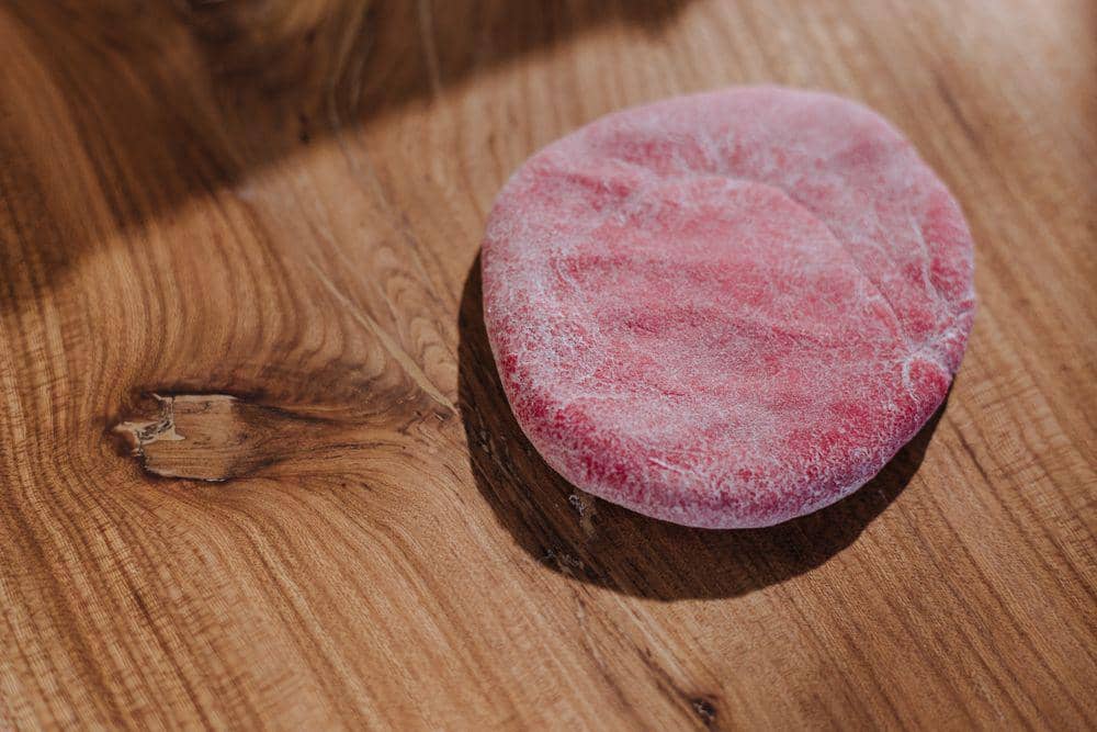 Tangan menutup mangkuk berisi adonan bakpao dengan kain putih untuk diistirahatkan sebelum dikukus di dapur.