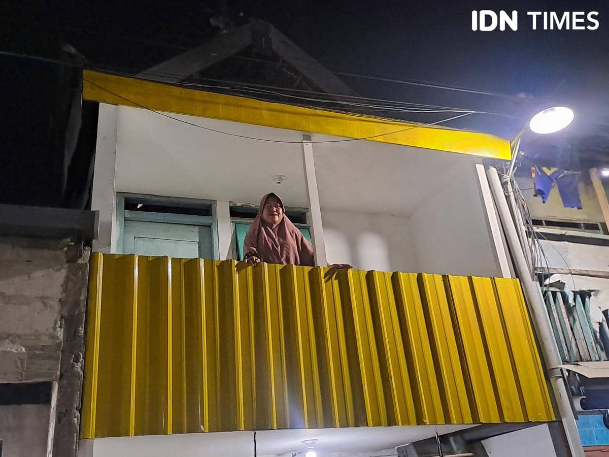 Riski, Ketua Koperasi Srikandi Kapirel, berdiri di rumah yang telah menerima manfaat program renovasi rumah.