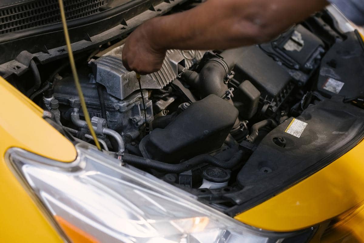 Seorang sedang memeriksa oli mobil.