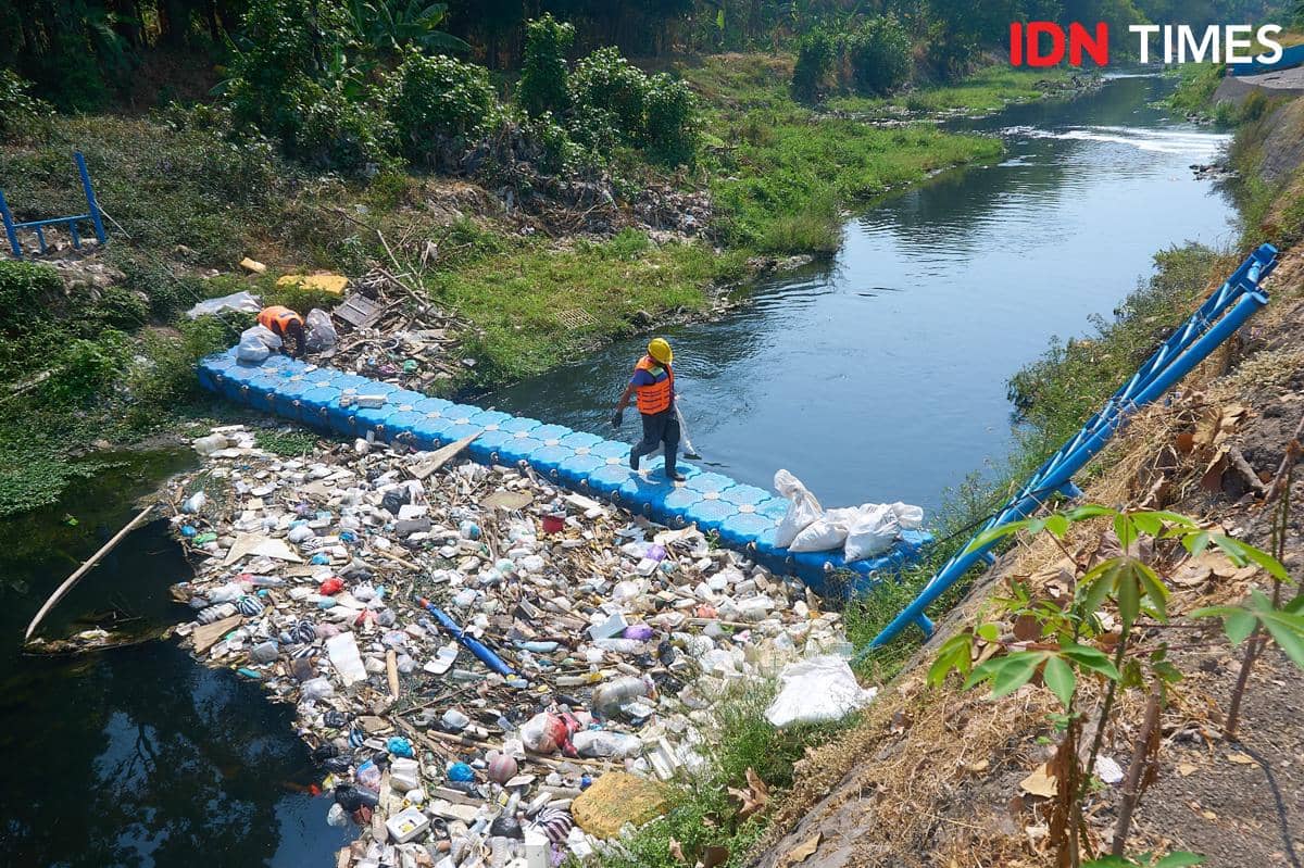 Anggota Kelompok Pengelola Sampah Joyo Gumregah membersihkan sampah yang terjaring trash boom saat pelaksanaan Program Sungai Lestari di ali