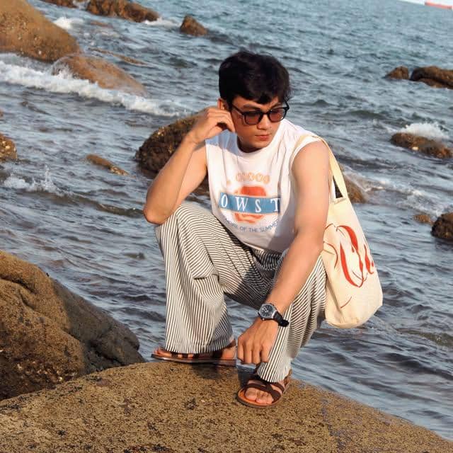 Vo Khanh Hung mengenakan busana OOTD santai bernuansa pantai dengan latar suasana pesisir dalam unggahan Instagram.