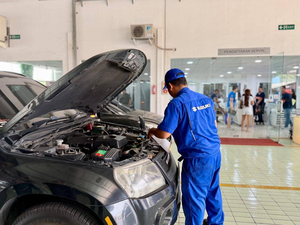 Ilustrasi layanan servis kendaraan di bengkel resmi Suzuki dengan area kerja dan peralatan perawatan otomotif.