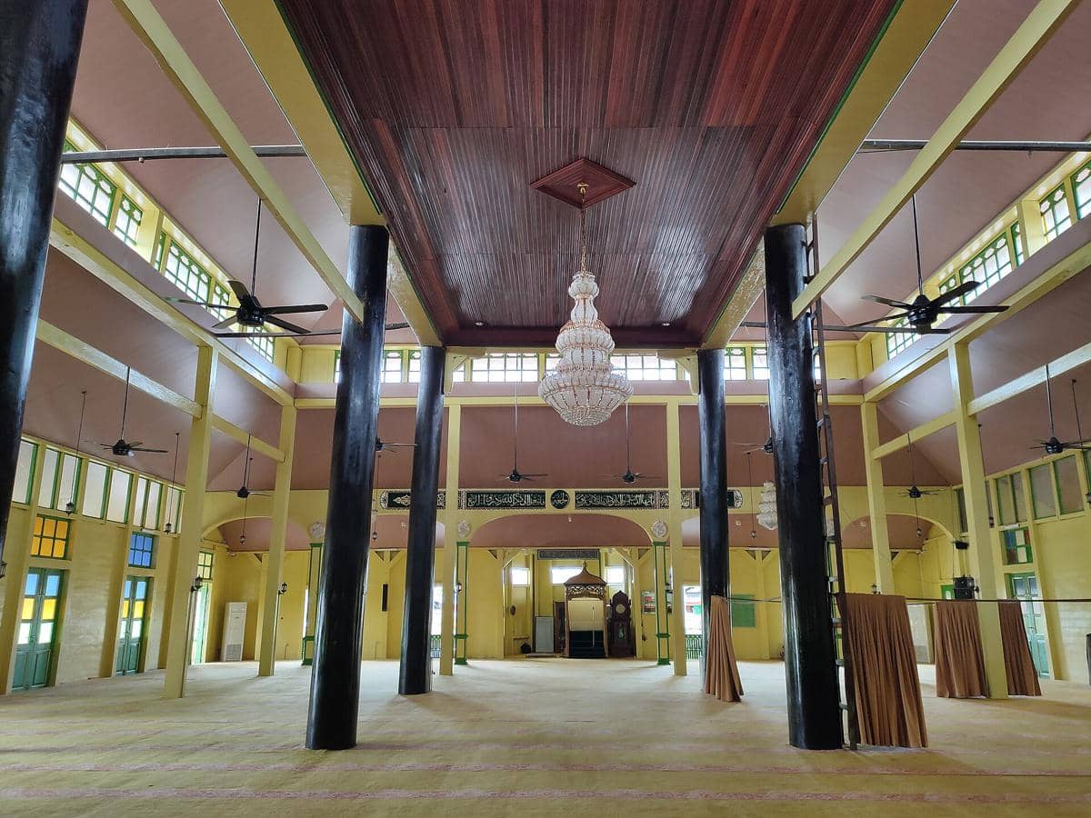 Pemandangan aula salat di dalam Masjid Jami Pontianak yang menampilkan mihrab, mimbar, dan lampu gantung.