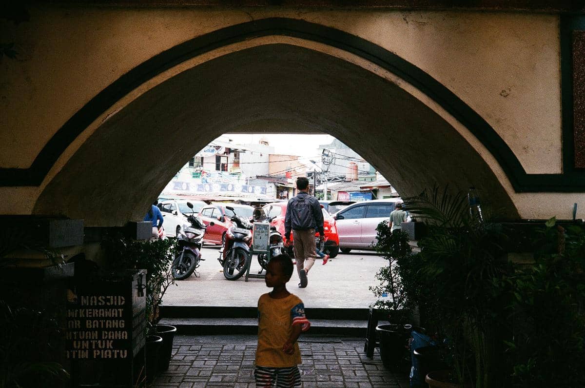 Pemandangan gerbang masuk Masjid Luar Batang dengan area depan masjid dan unsur arsitektur bangunannya.