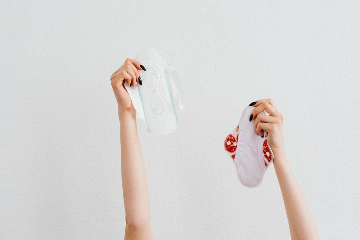 Beberapa pembalut wanita tersusun di atas permukaan berwarna merah muda sebagai ilustrasi kebutuhan menstruasi.
