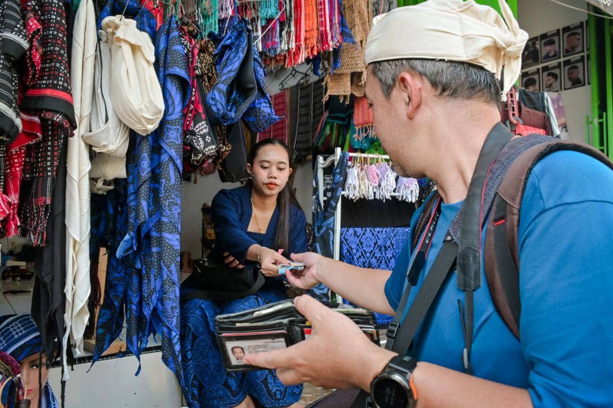 ilustrasi seorang pria membeli tekstil di sebuah kios pasar terbuka dari seorang penjual wanita