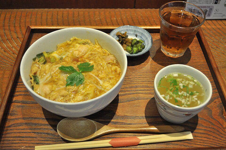 Semangkuk oyakodon berisi nasi, potongan ayam, dan telur lembut, disajikan hangat dalam mangkuk keramik.
