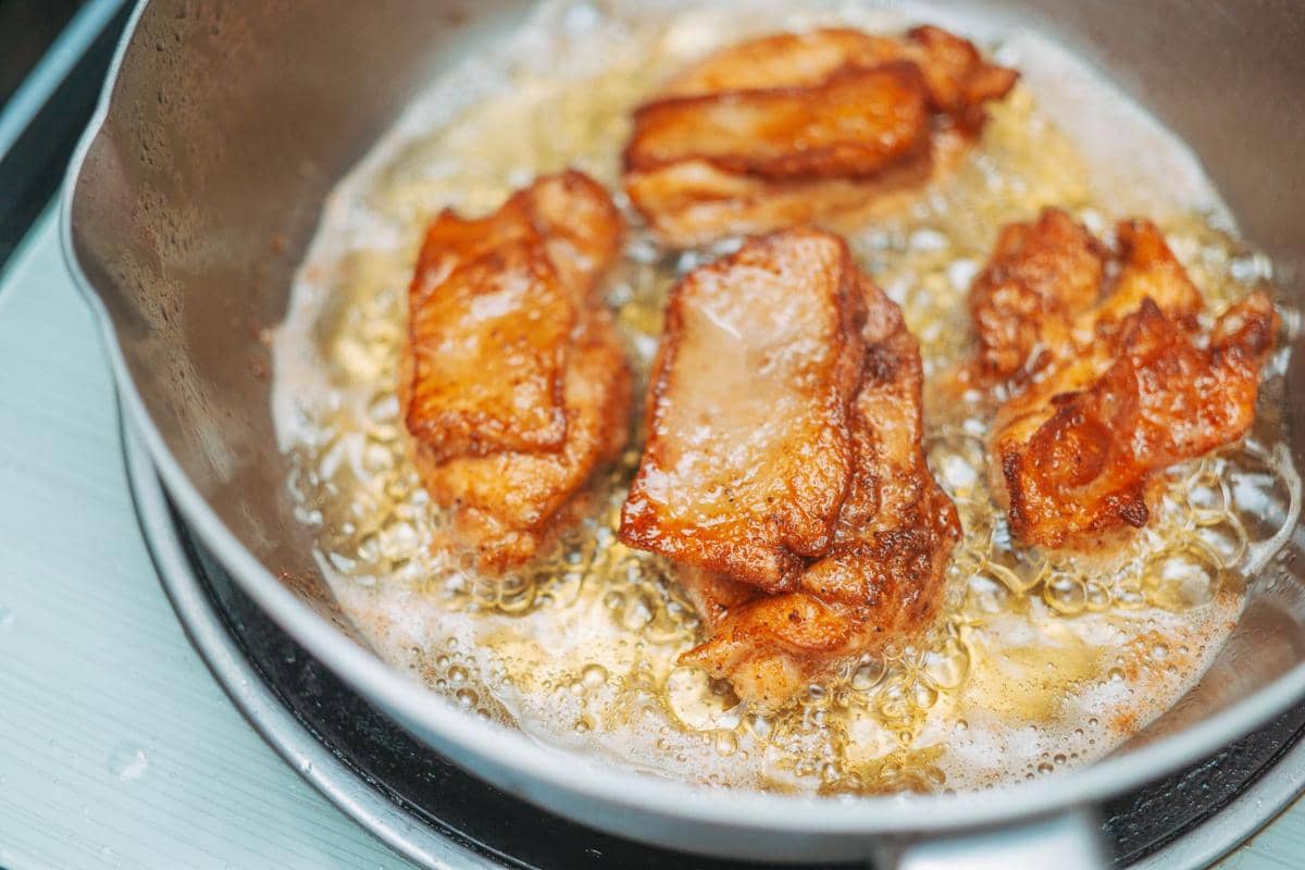 Ilustrasi proses menggoreng makanan dalam wajan panas di atas kompor, sebagai kegiatan memasak di dapur.