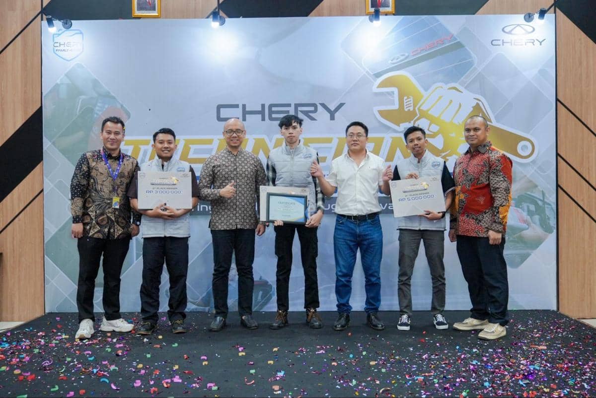 Tiga pemenang kompetisi teknisi Chery berpose bersama di atas panggung sambil memegang penghargaan mereka.