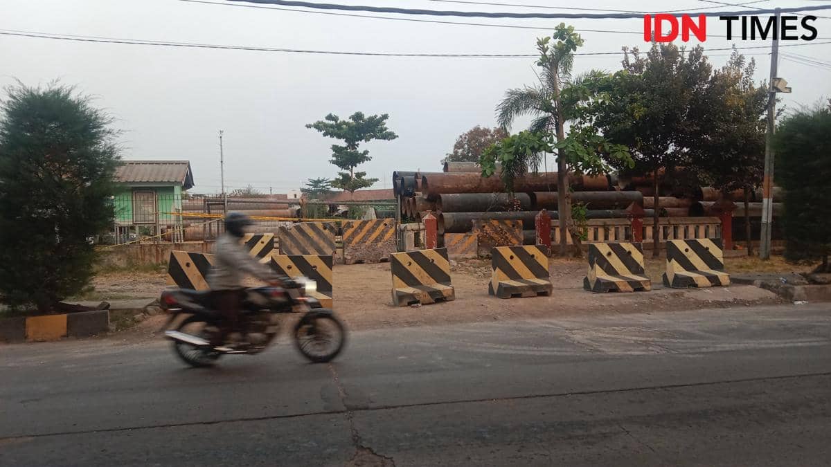 Seorang polisi mengendarai sepeda motor melintas di lokasi penumpukan besi bekas dermaga di tepi jalan.